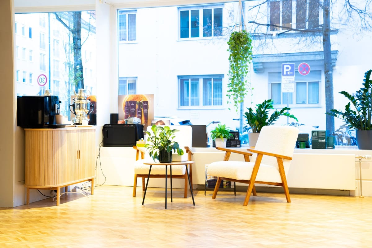 Die Lounge am Fenster mit zwei Sesseln, Pflanzen und der Kaffeemaschine